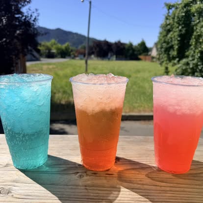 Three colorful Sips drinks over crushed ice on a picnic table